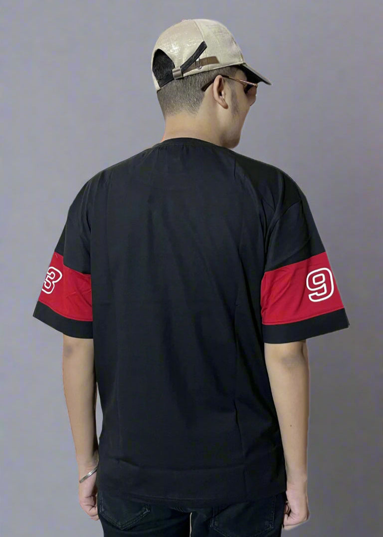 Person wearing a black baseball jersey with red sleeves and a cap on a light gray background