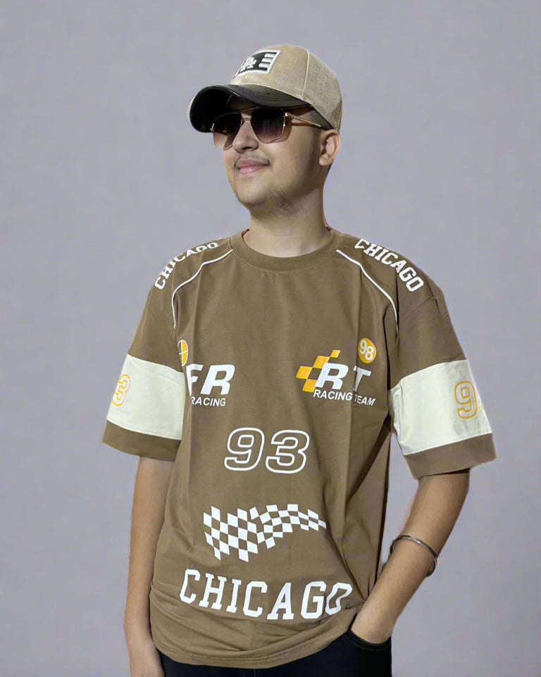 Person wearing a brown racing-themed shirt with logos and text on a light gray background