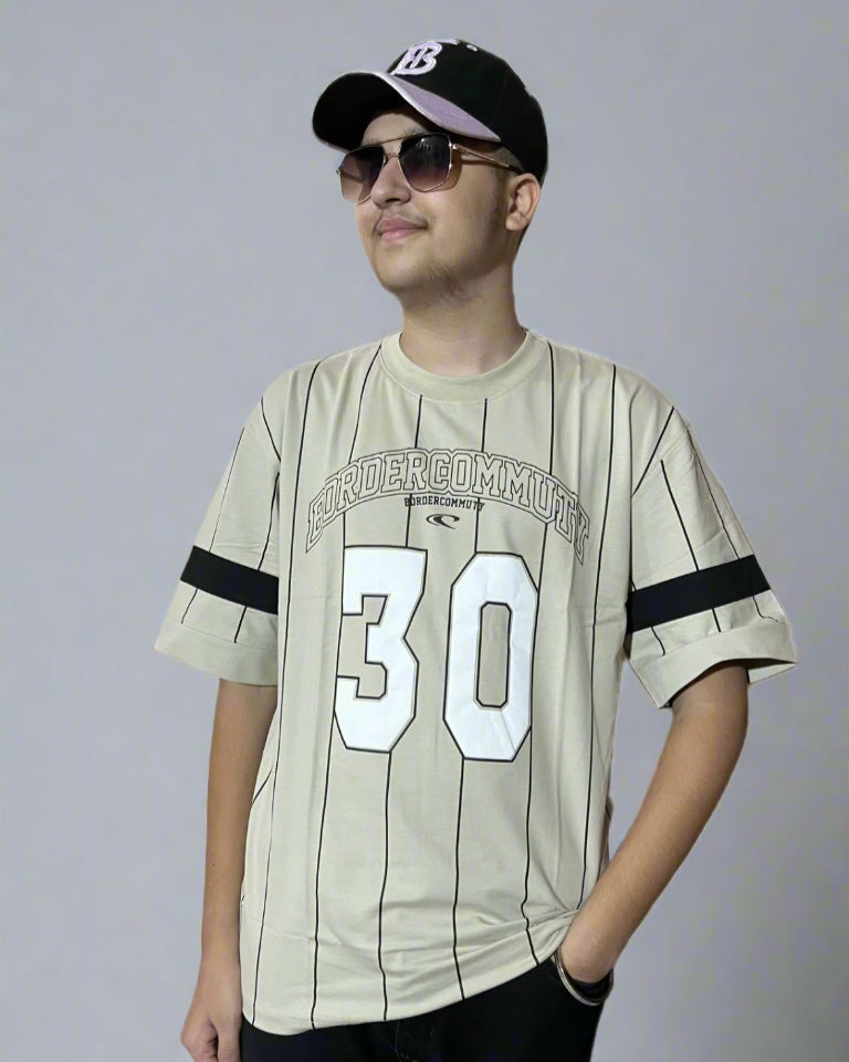 Person wearing a beige sports jersey with number 30 and a cap on a gray background