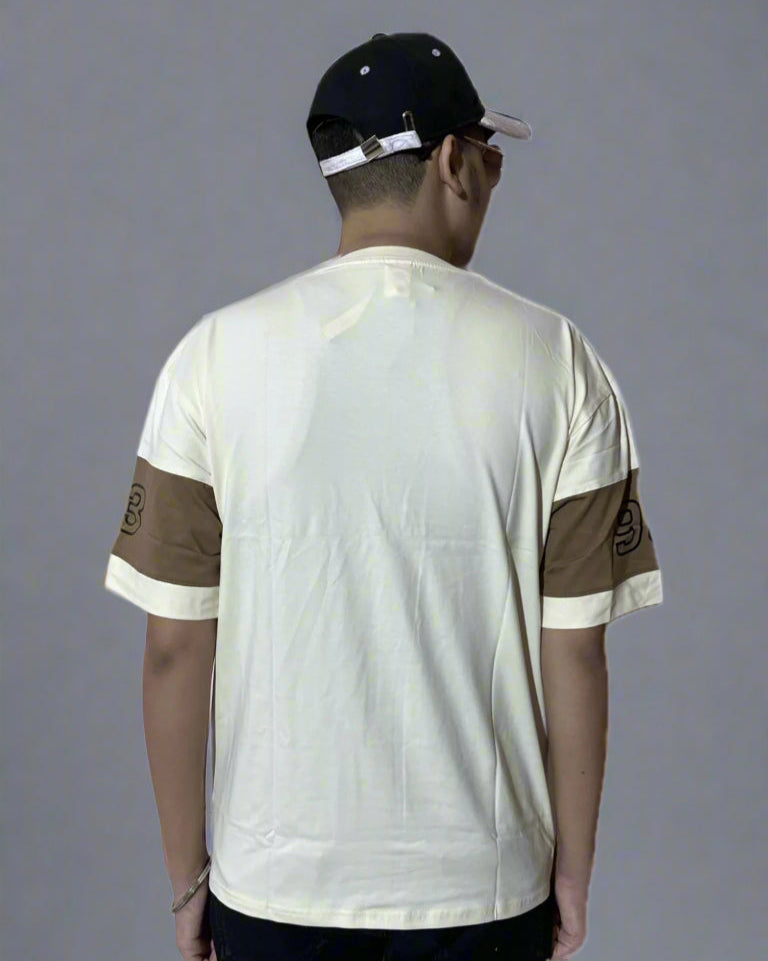 Person wearing a white t-shirt with brown accents and a black cap on a gray background