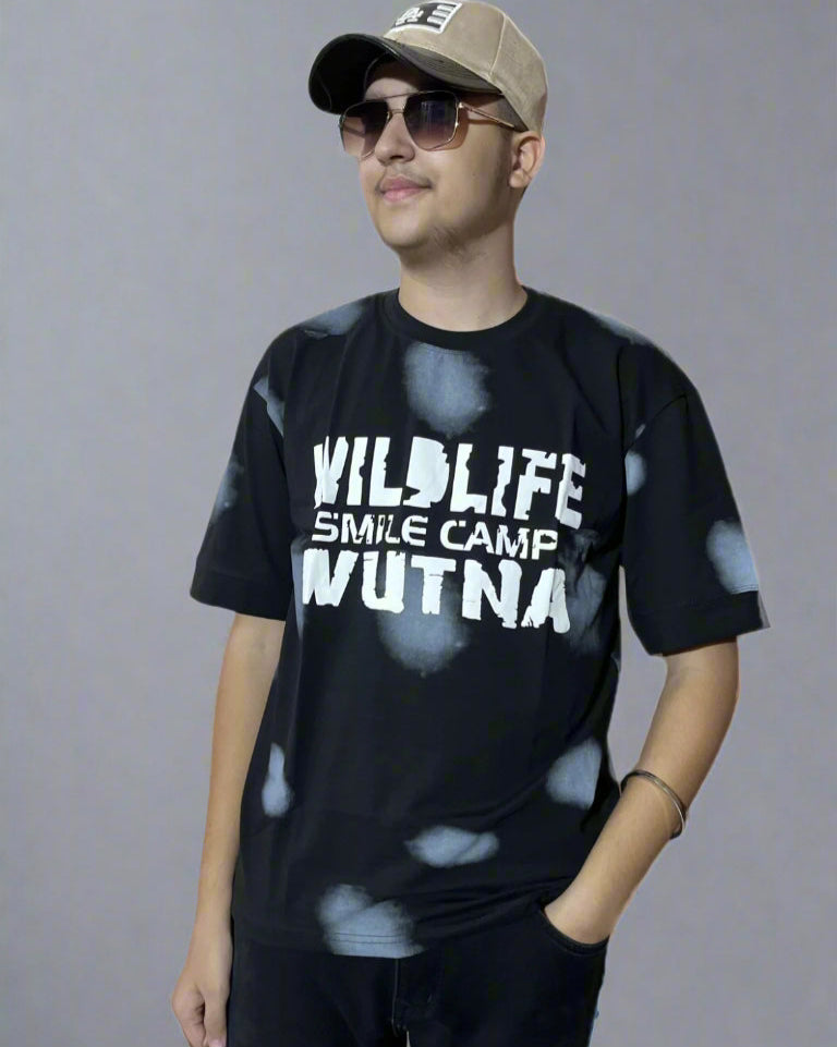 Person wearing a black t-shirt with text and a cap on a gray background