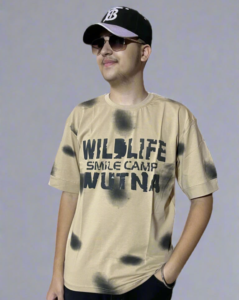 Person wearing a beige t-shirt with text and a black cap on a light gray background