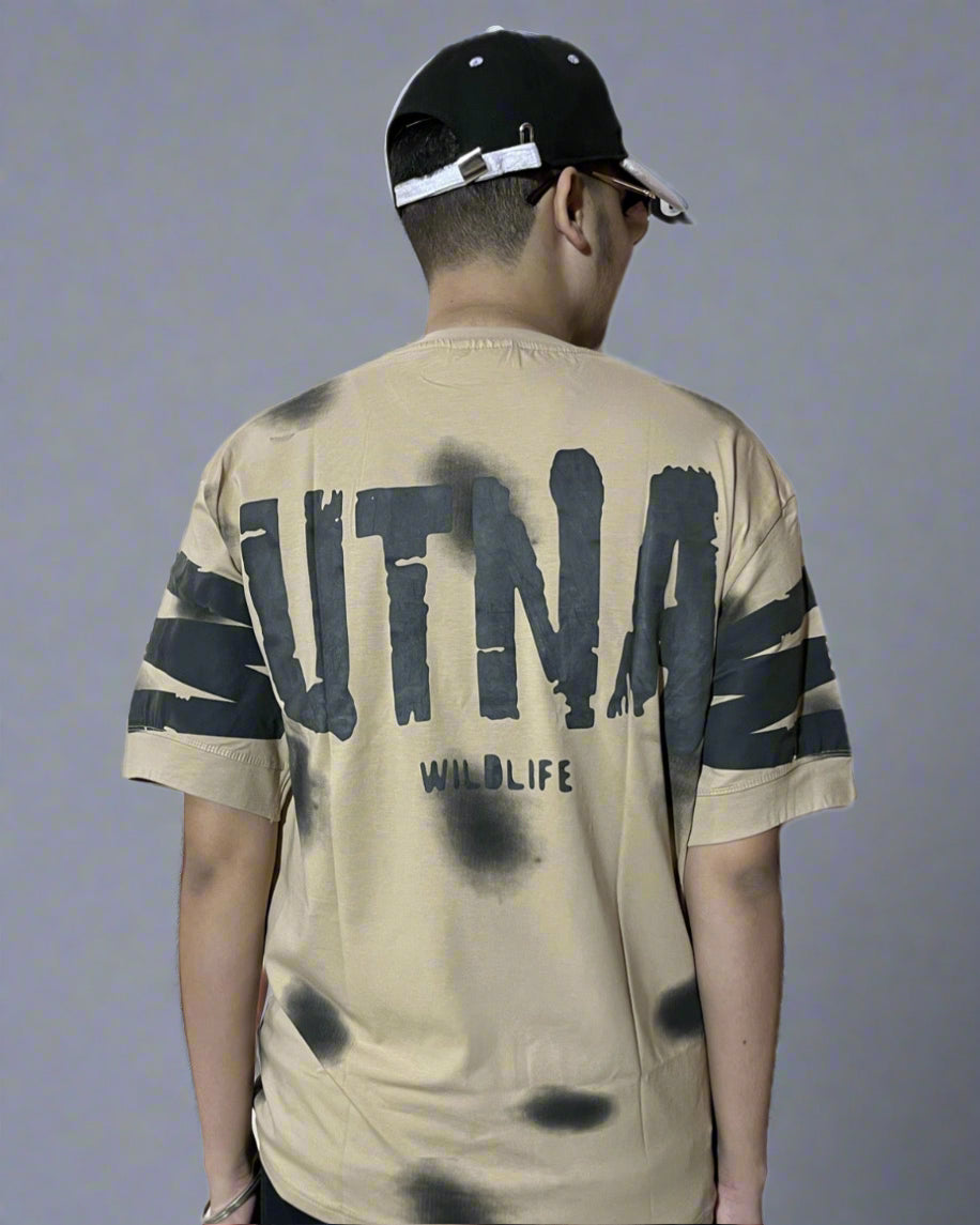 Person wearing a beige t-shirt with black text and graphics on a white background