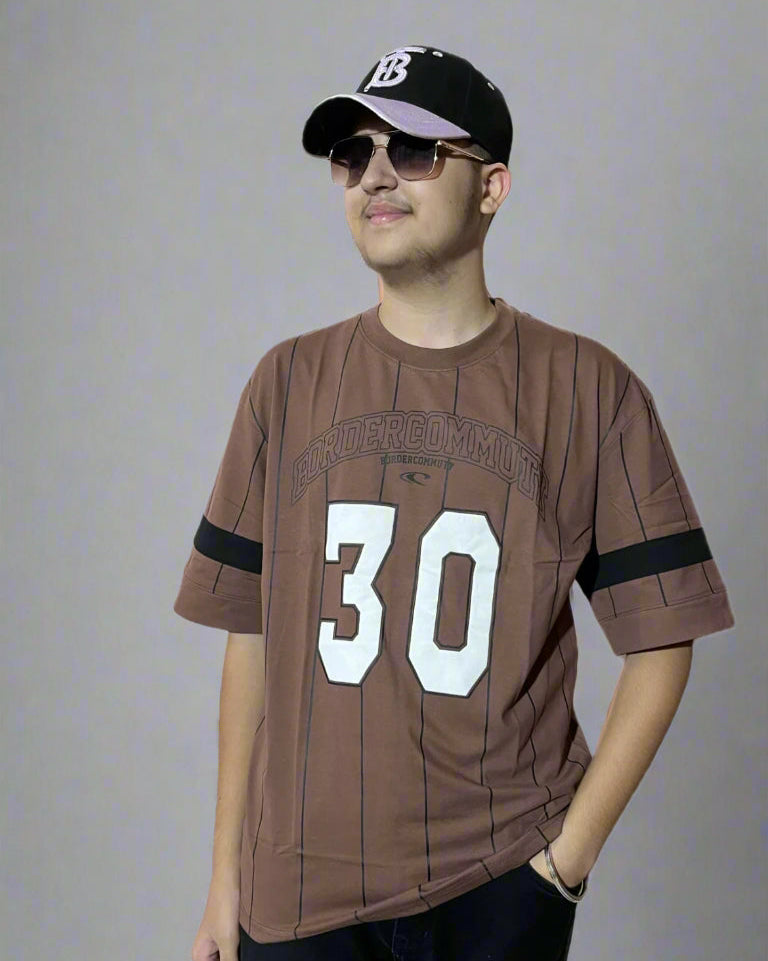 Man wearing a brown sports jersey with the number 30 and a black cap on a gray background