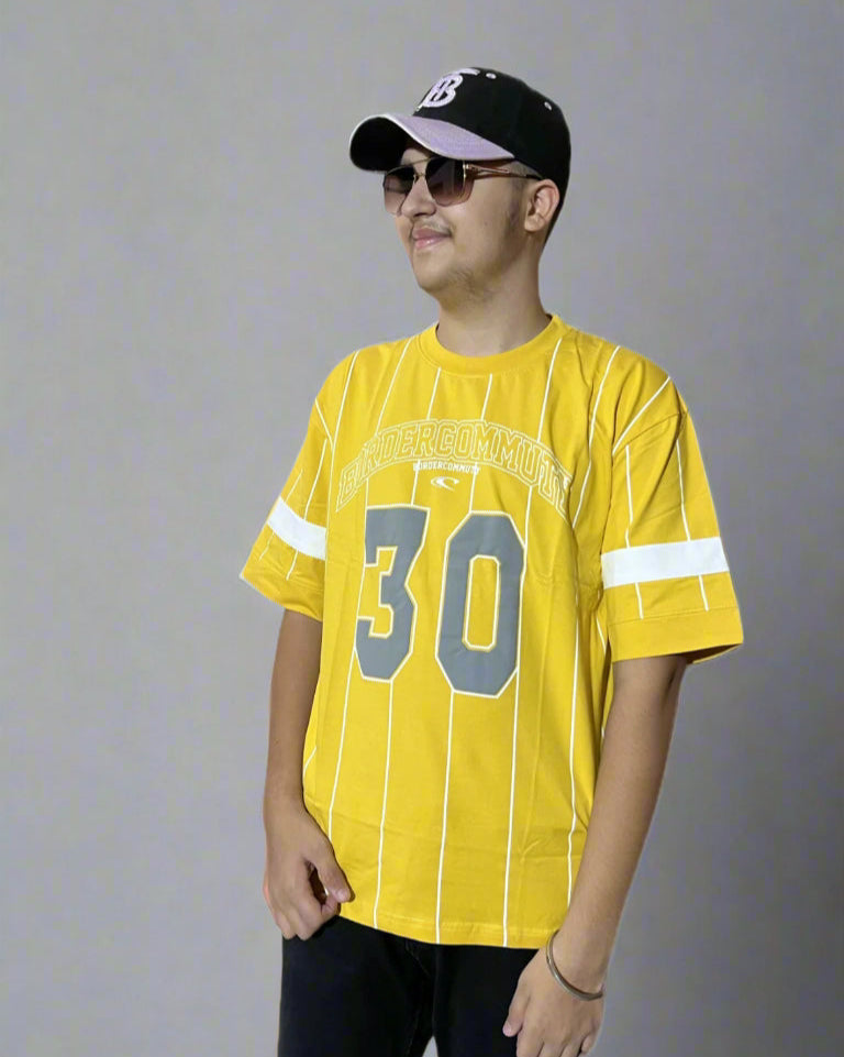 Person wearing a yellow sports jersey with number 30 and a black cap on a light blue background