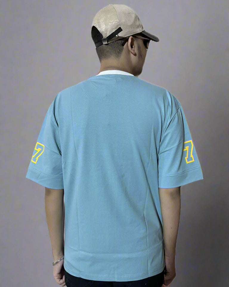 Person wearing a light blue t-shirt with yellow numbers on the back, standing against a white background.
