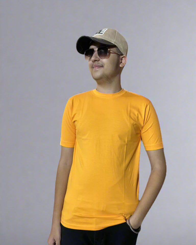 Man wearing a yellow t-shirt, black pants, and a beige cap with sunglasses on a light blue background