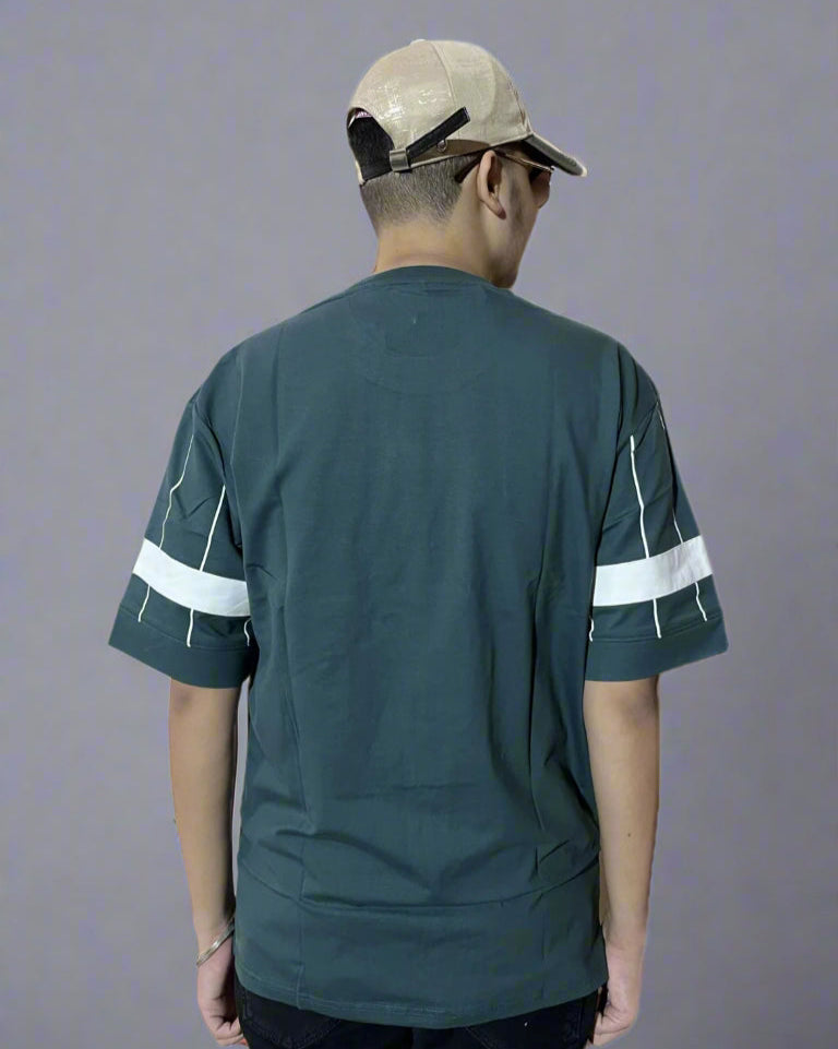 Person wearing a green sports jersey with white stripes on sleeves and a beige cap, standing against a plain background.