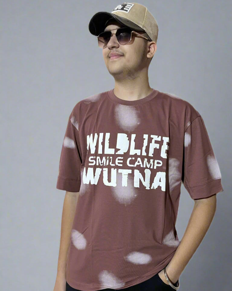 Man wearing a brown t-shirt with text and a cap on a light gray background