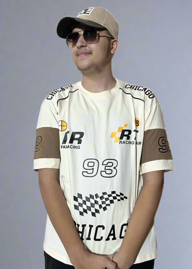 Person wearing a white racing-themed shirt with various logos on a gray background